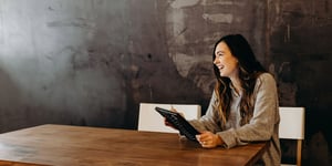 Frau mit Tablet an einem Holztisch sitzend