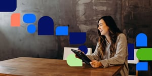 Frau mit Tablet an Holztisch sitzend